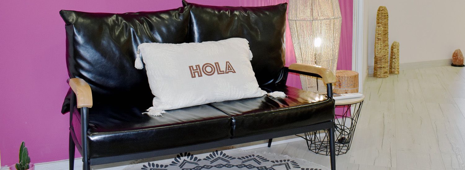 Imagen del interior del estudio de KeniSanP donde se ve un sofá de piel con un cojín que pone HOLA.